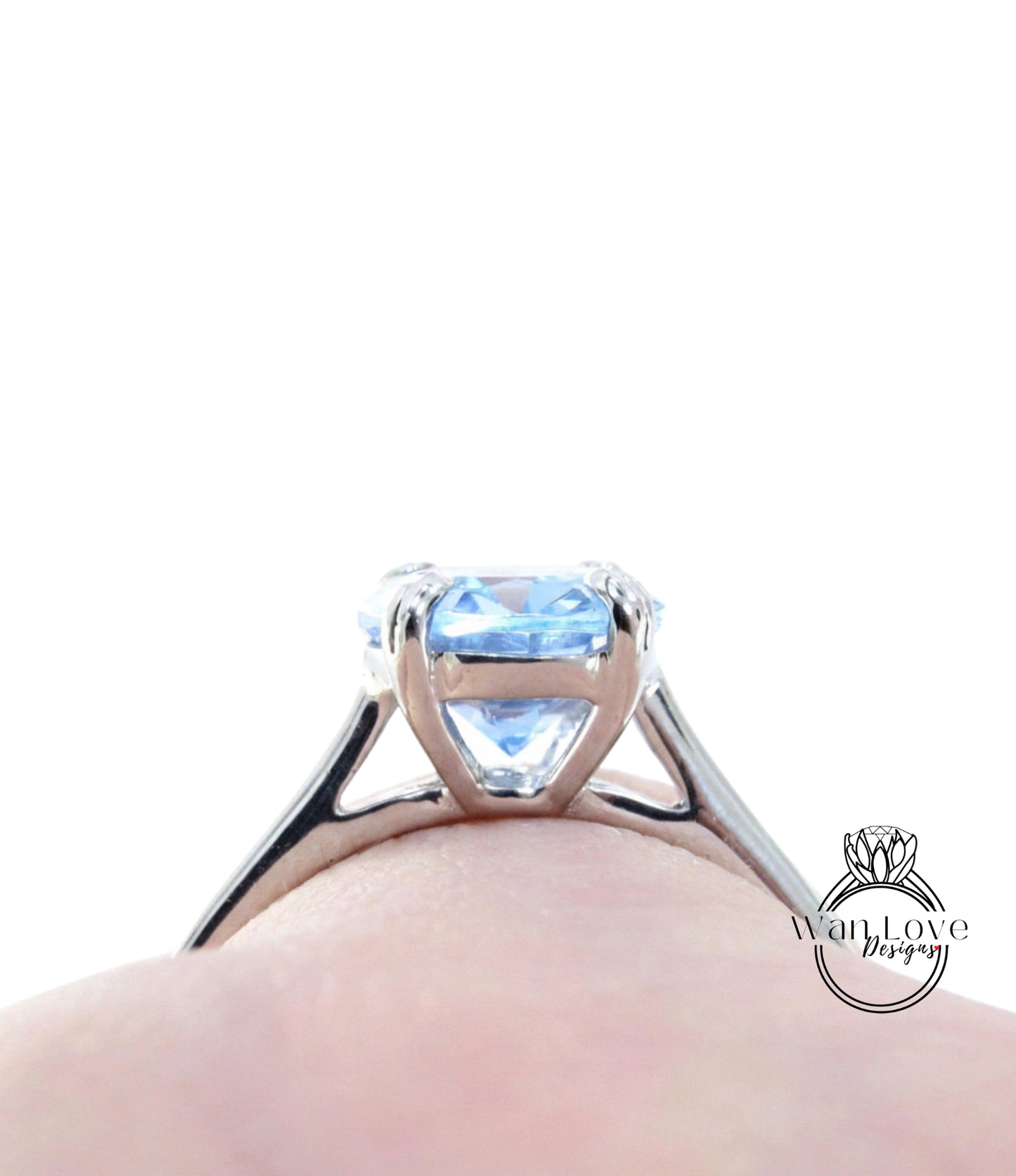 A close-up view of a silver engagement ring with a blue gemstone, showcasing the intricate design and details of the ring.