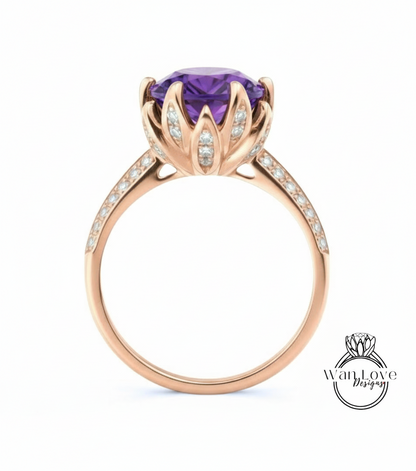 A gold ring with a large purple gemstone, likely an amethyst, at the center. The ring has a delicate flower-like design around the gemstone, and the band is adorned with small diamonds.