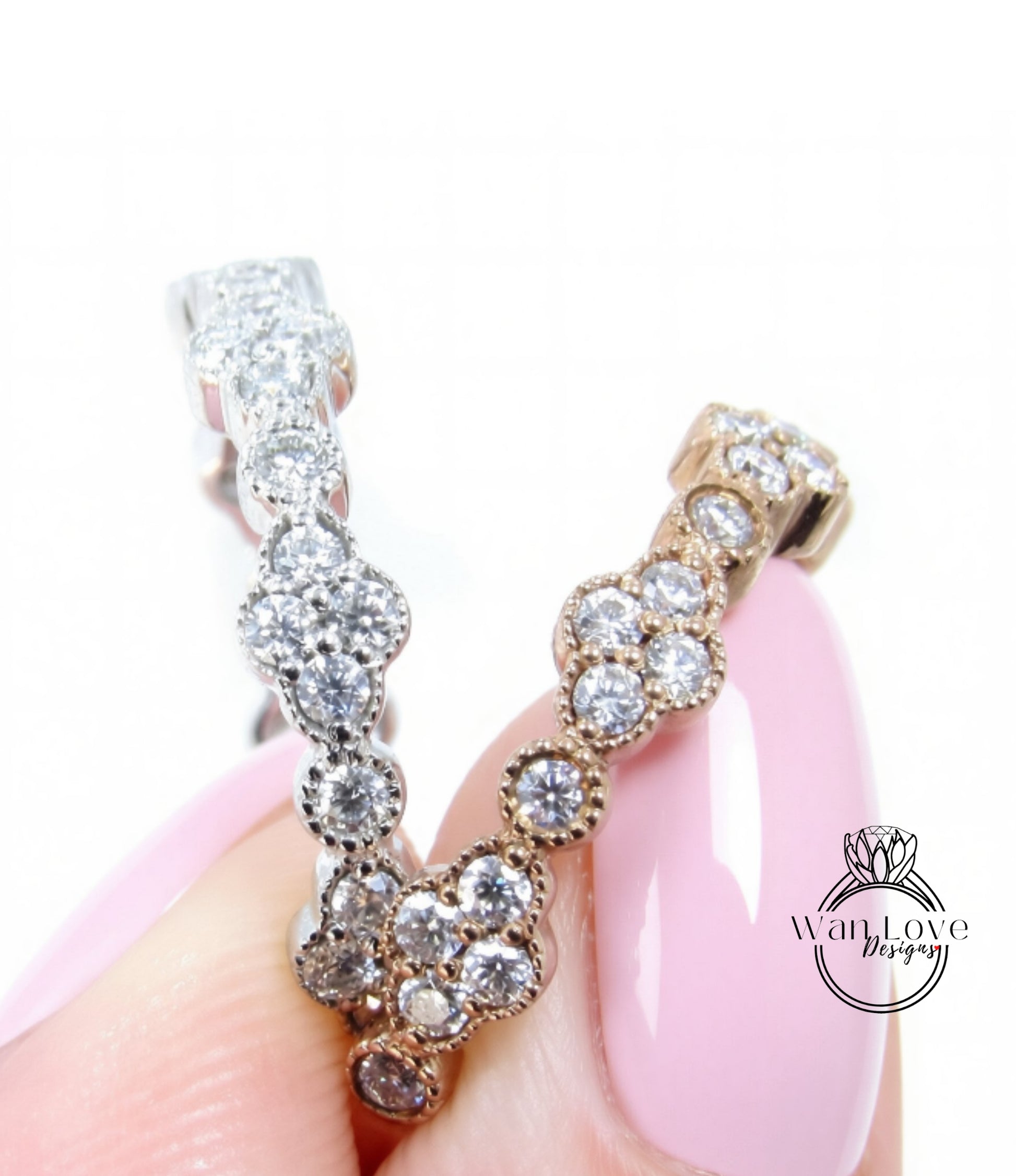 A close-up image of a person's hand holding a pair of diamond-encrusted earrings.