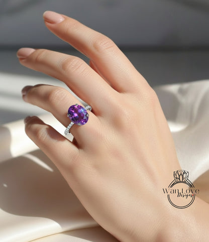 A close-up of a hand wearing a ring with a large purple gemstone, likely an amethyst, on the ring finger.