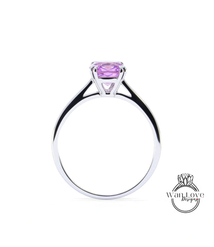 A silver ring with a large purple gemstone, likely a sapphire, set in the center.