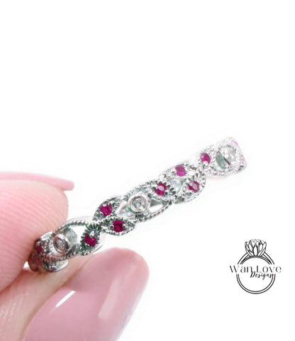 A close-up image of a person's hand holding a silver ring adorned with red gemstones.