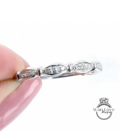 A close-up image of a person's hand holding a silver ring with a row of small diamonds on the band.