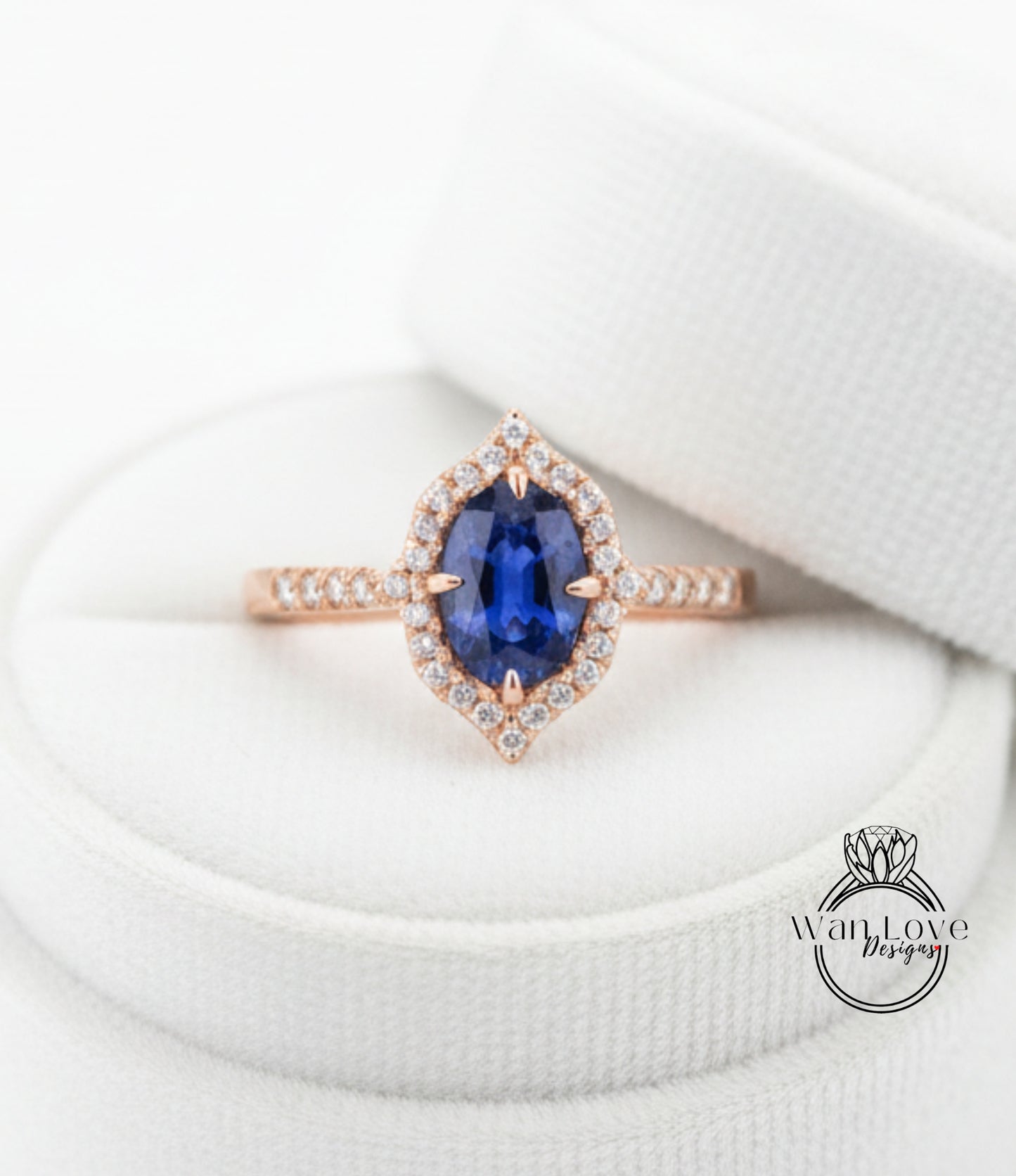 A close-up image of a rose gold ring with a large oval-shaped blue gemstone, surrounded by smaller diamonds, placed on a white surface.