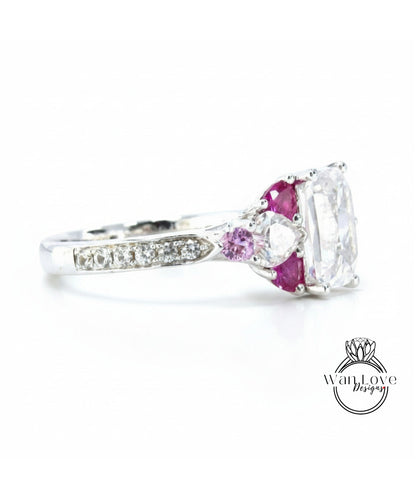 A close-up view of a silver ring with a large central gemstone surrounded by smaller gemstones and a row of smaller diamonds along the band.