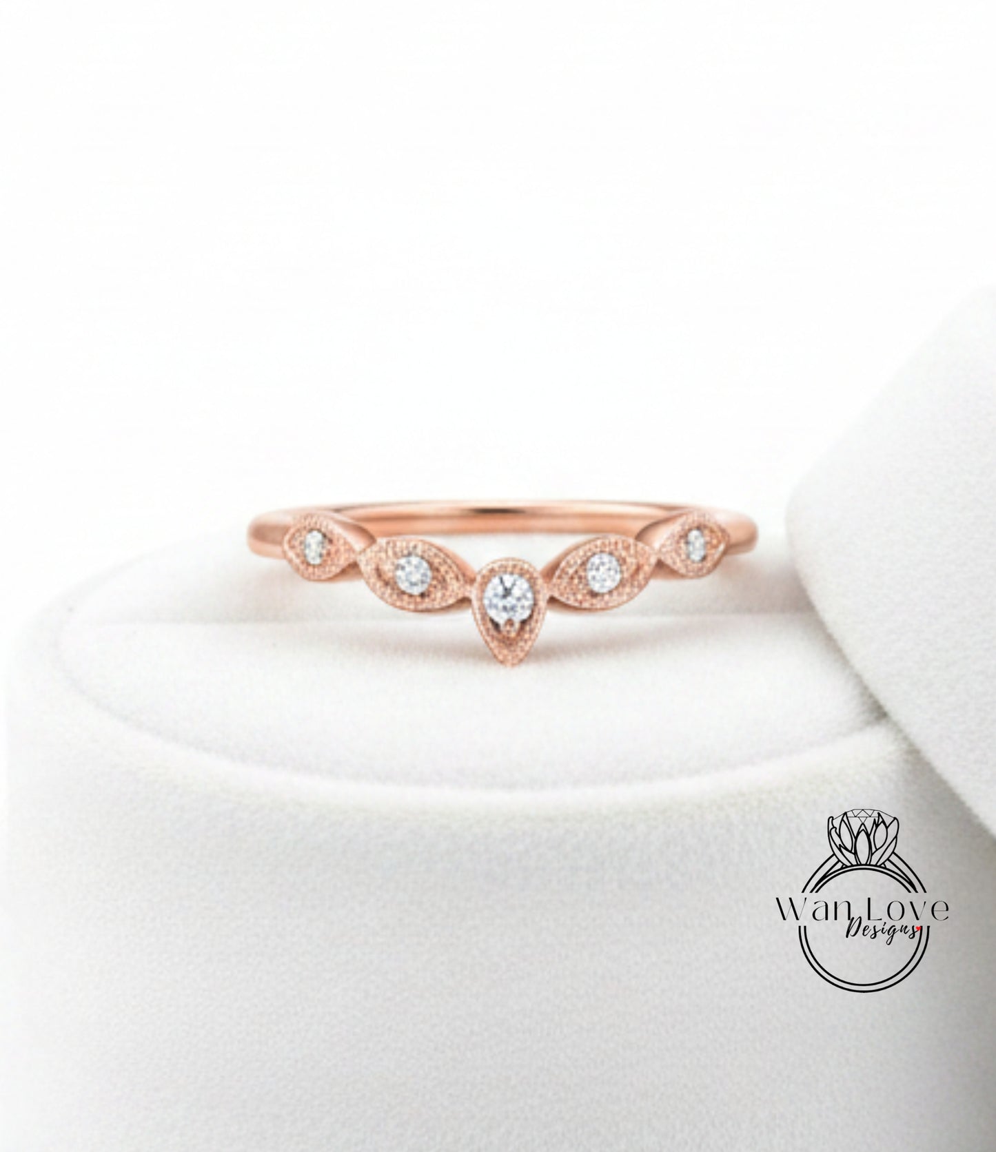 A rose gold ring with a central diamond and a row of smaller diamonds above it, displayed on a white surface.