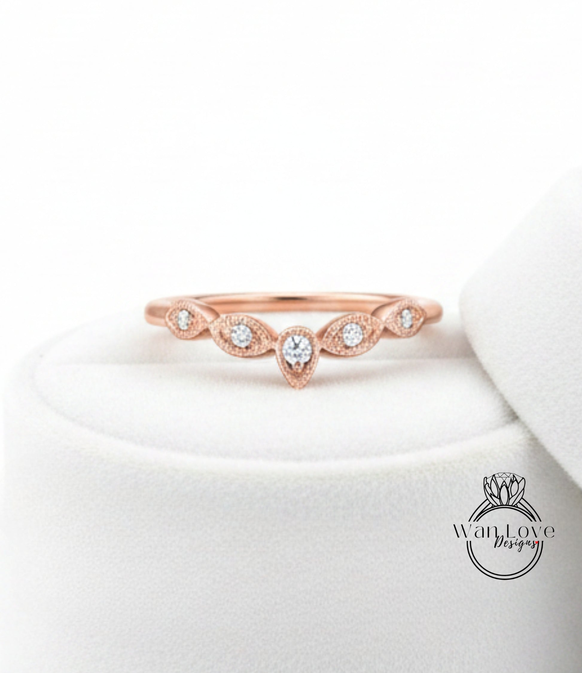 A rose gold ring with a central diamond and a row of smaller diamonds above it, displayed on a white surface.