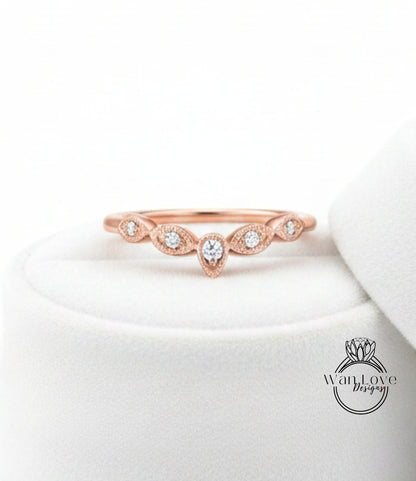 A rose gold ring with a central diamond and a row of smaller diamonds above it, displayed on a white surface.