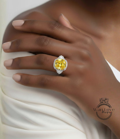 A close-up of a person's hand wearing a large yellow diamond ring on the ring finger.