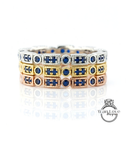 A stack of three rings with blue gemstones set in gold and silver, arranged in a circular pattern.