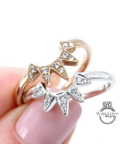 A close-up image of a person's hand holding two rings with diamond-encrusted designs.