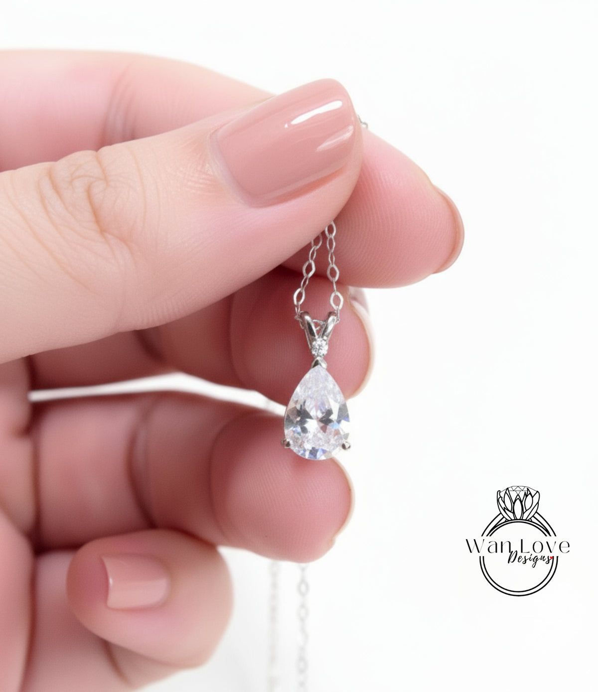A hand holding a delicate necklace with a single, large, clear gemstone pendant.