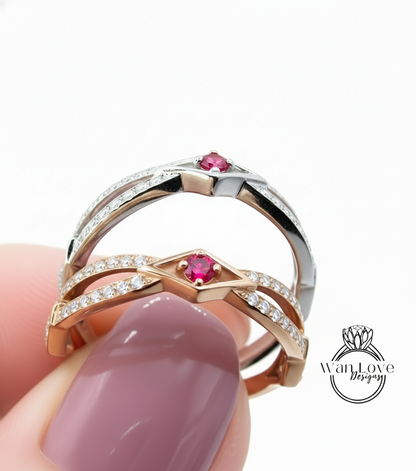 A close-up of a person's hand holding a ring with a pink gemstone and a silver band, with the ring being held against a white background.