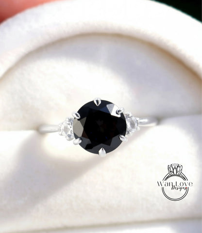 A close-up view of a silver ring with a large black gemstone, possibly a diamond, set in the center.