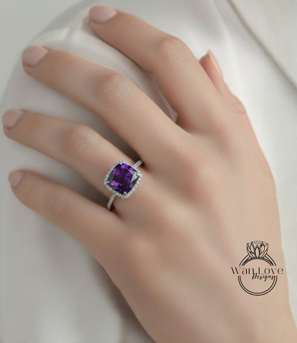 A close-up of a hand wearing a ring with a large purple gemstone, likely an amethyst, on the ring finger.