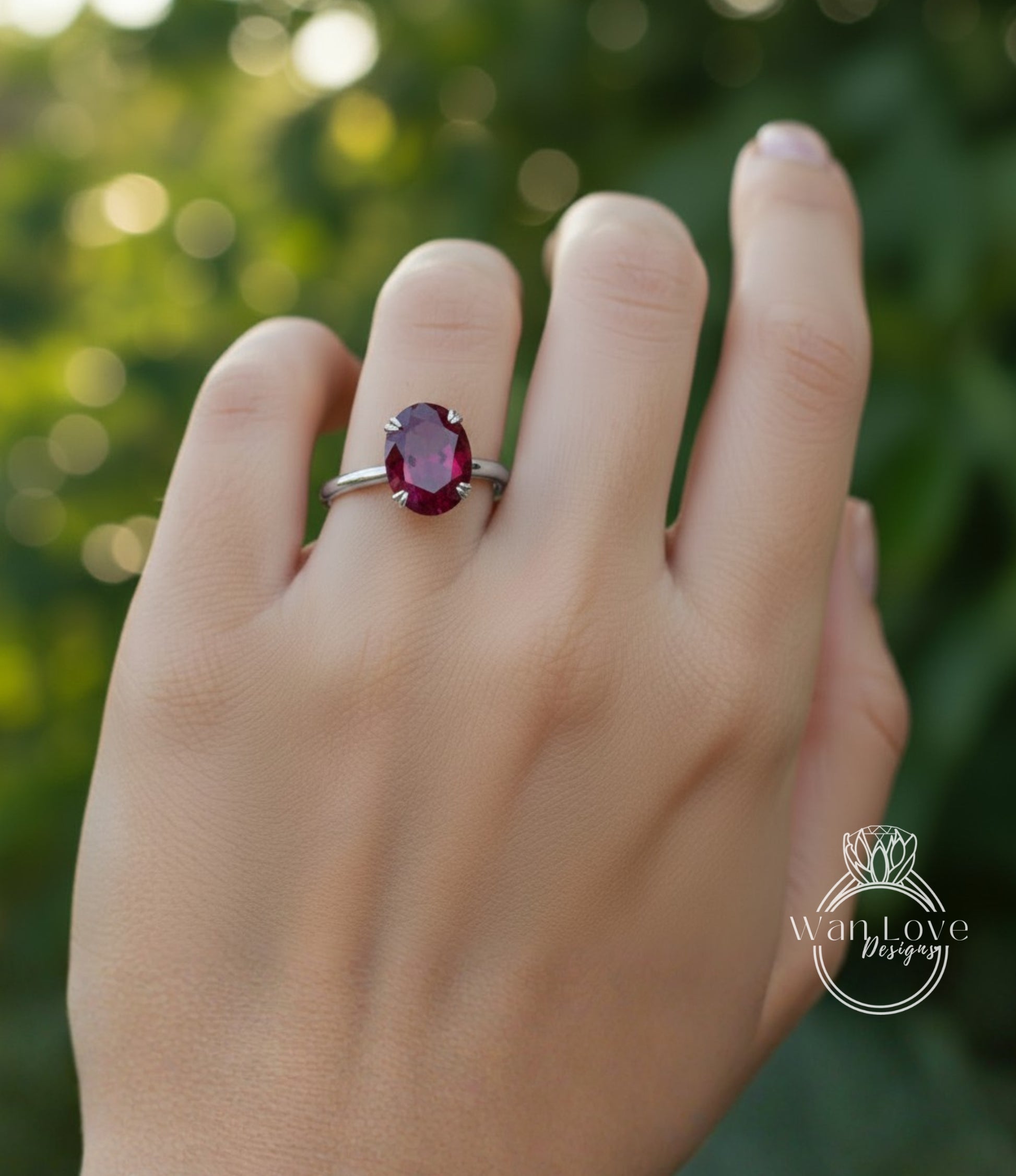 A close-up of a person's hand wearing a ring with a large, deep red gemstone.