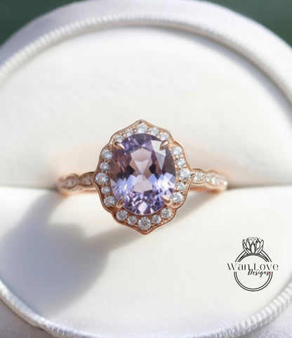 A close-up image of a gold ring with a large oval-shaped purple gemstone, surrounded by smaller diamonds, placed in a white box.