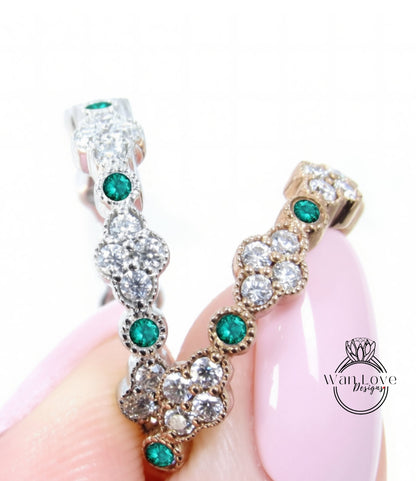 A close-up image of a person's hand holding a pair of earrings with green gemstones and sparkling diamonds.
