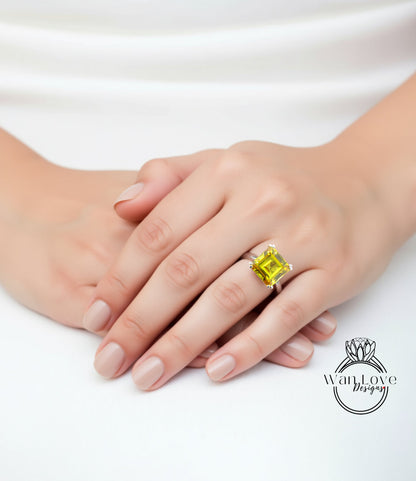 A close-up of a person's hand wearing a large yellow gemstone ring, resting on a white surface.