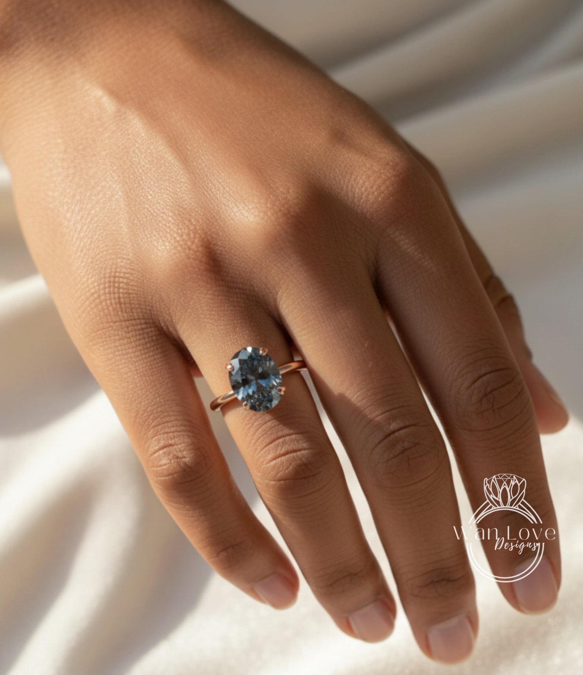 A close-up of a hand wearing a ring with a large blue gemstone.