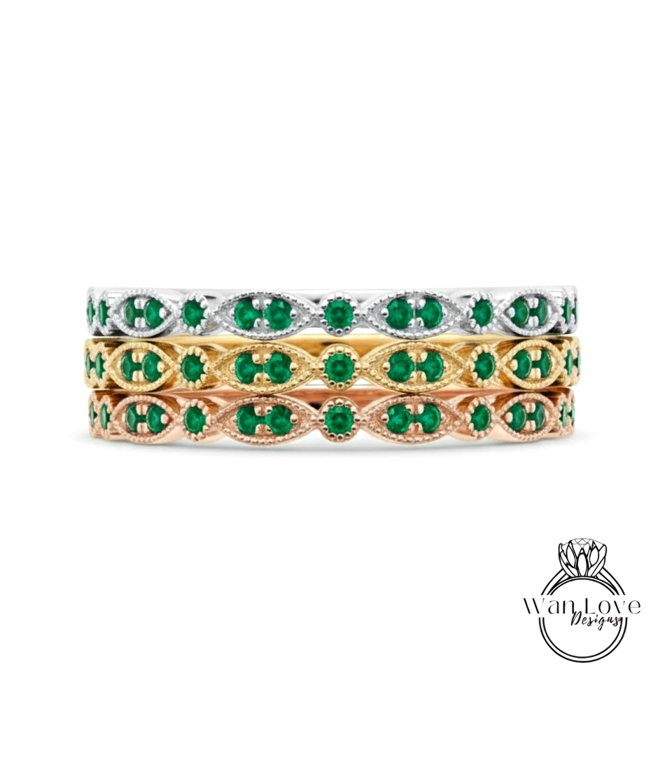 A stack of three rings with green gemstones set in a decorative pattern.