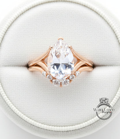 A close-up image of a gold ring with a large pear-shaped diamond set in the center, surrounded by smaller diamonds.
