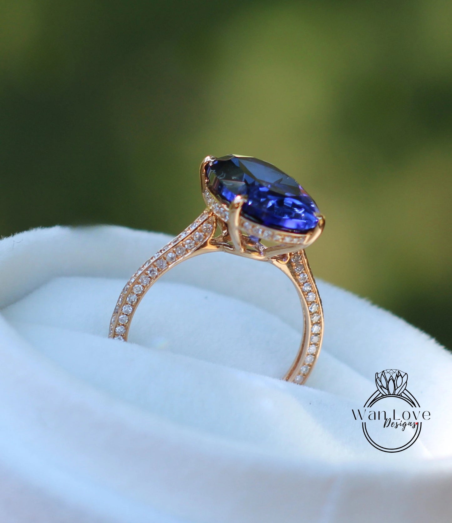A close-up image of a gold ring with a large blue gemstone, placed on a white fabric surface.