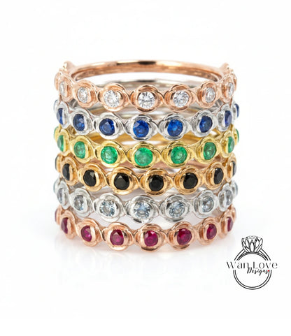 A stack of rings with various colored gemstones set in a metallic band.