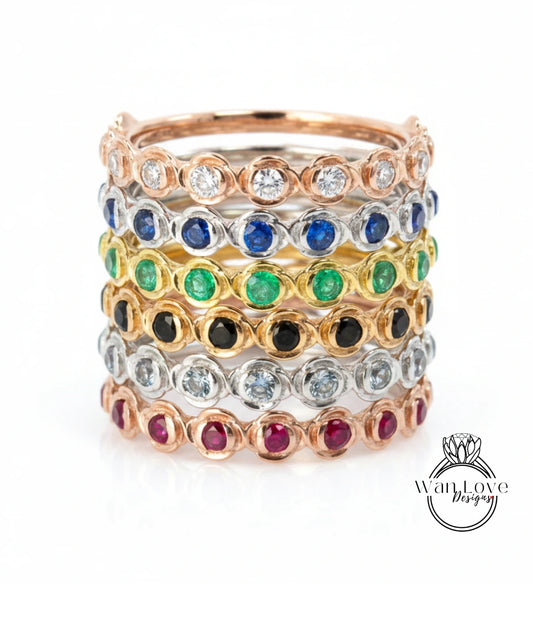 A stack of rings with various colored gemstones set in a metallic band.