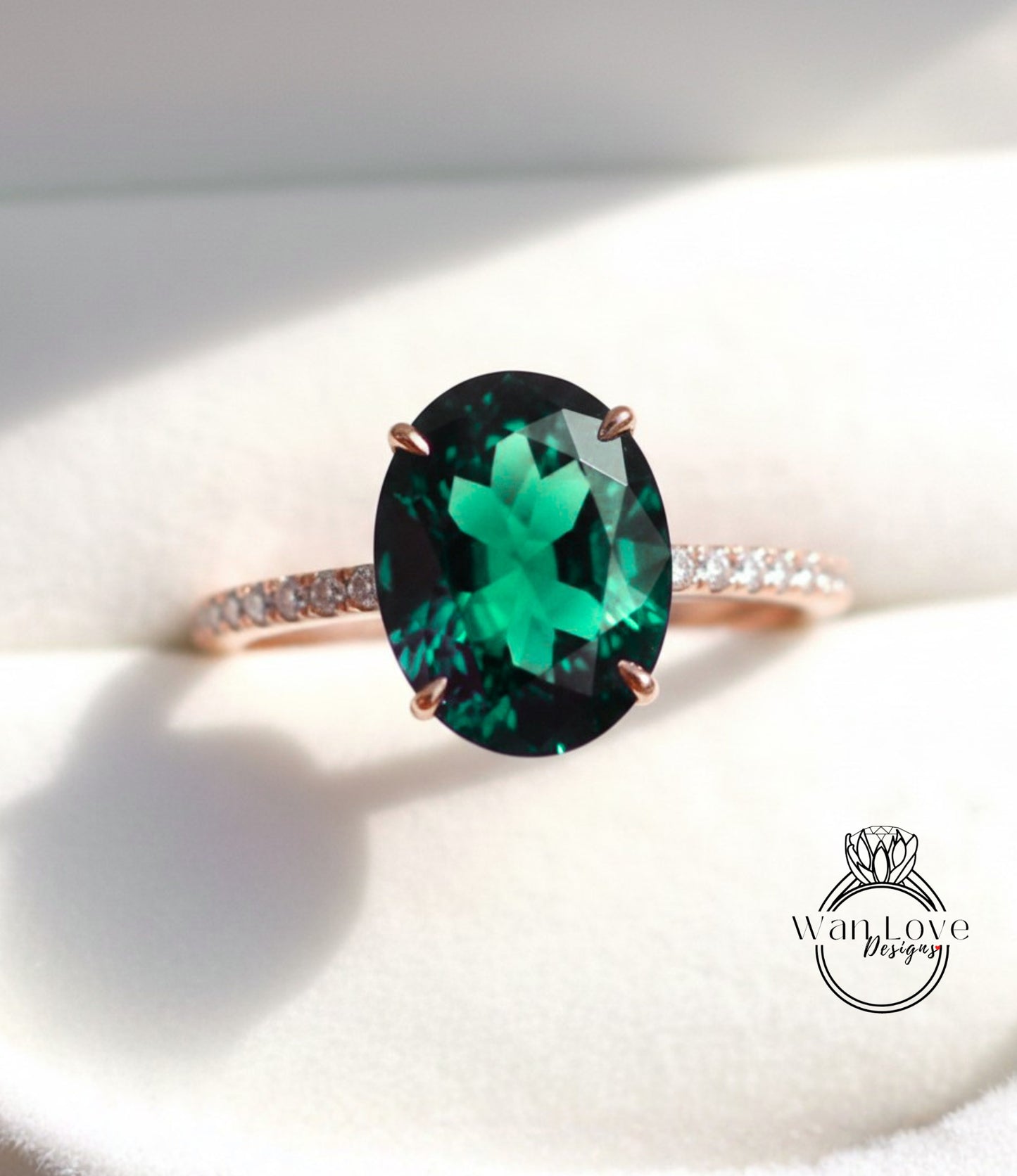 A close-up image of a rose gold ring with a large oval-shaped green gemstone, possibly a diamond, set in the center of the band.