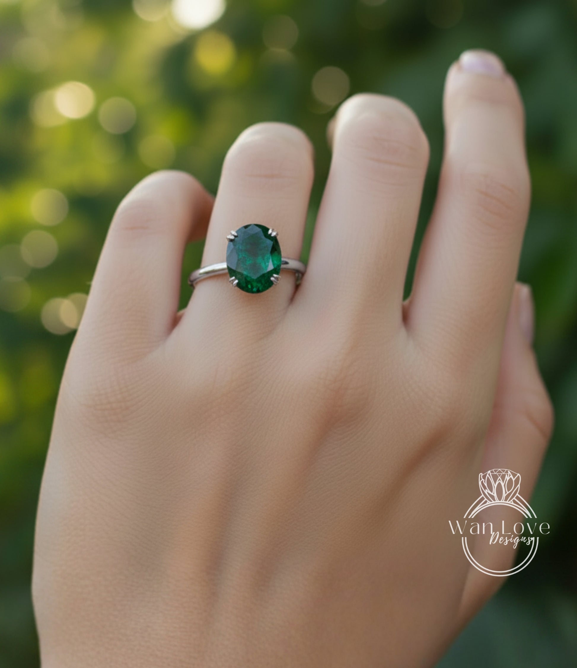 A close-up of a person's hand wearing a ring with a large oval-shaped green gemstone.