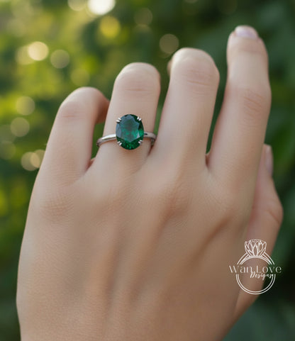 A close-up of a person's hand wearing a ring with a large oval-shaped green gemstone.