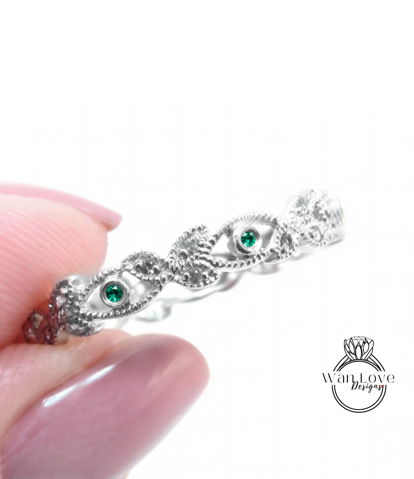 A close-up image of a person's hand holding a silver ring with intricate designs and a green gemstone.