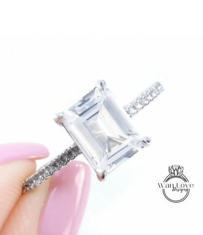 A close-up of a diamond engagement ring being held in a hand, with a focus on the diamond itself.