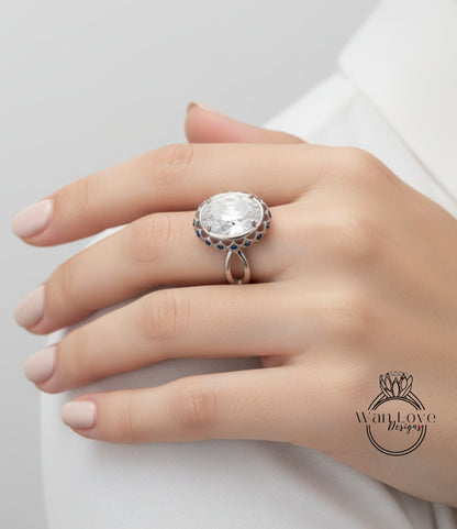 A close-up of a person's hand wearing a large, ornate ring with a large central stone.