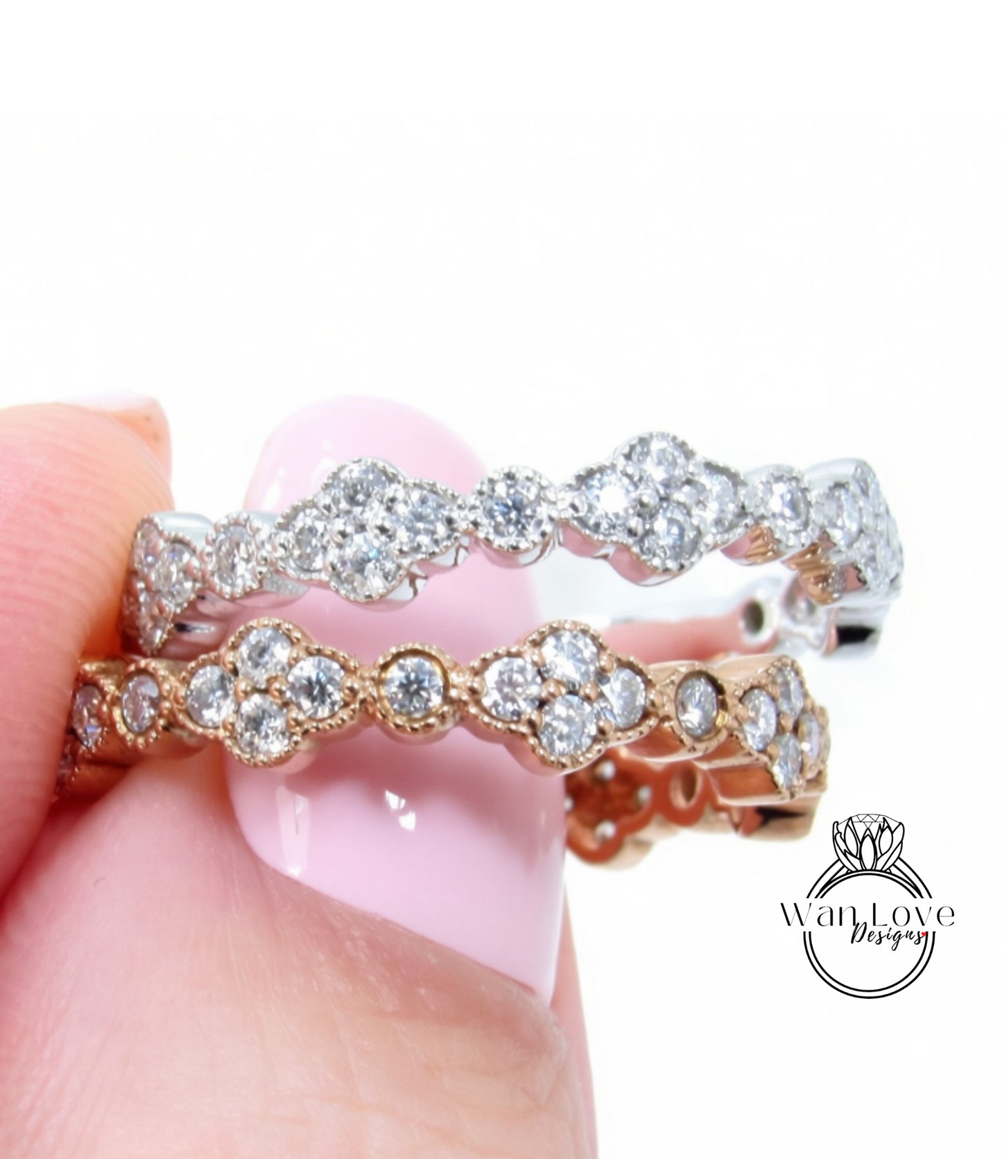 A close-up of a person's hand holding a ring with a row of diamonds on it.