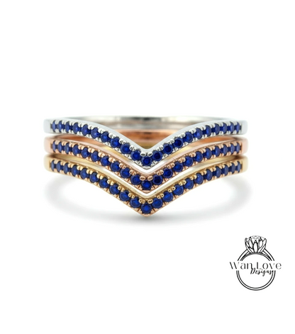 A ring with three layers of rings, each with blue gemstones. The topmost ring is silver, the middle ring is gold, and the bottom ring is rose gold. The gemstones are blue, and the rings are arranged in a v-shape.