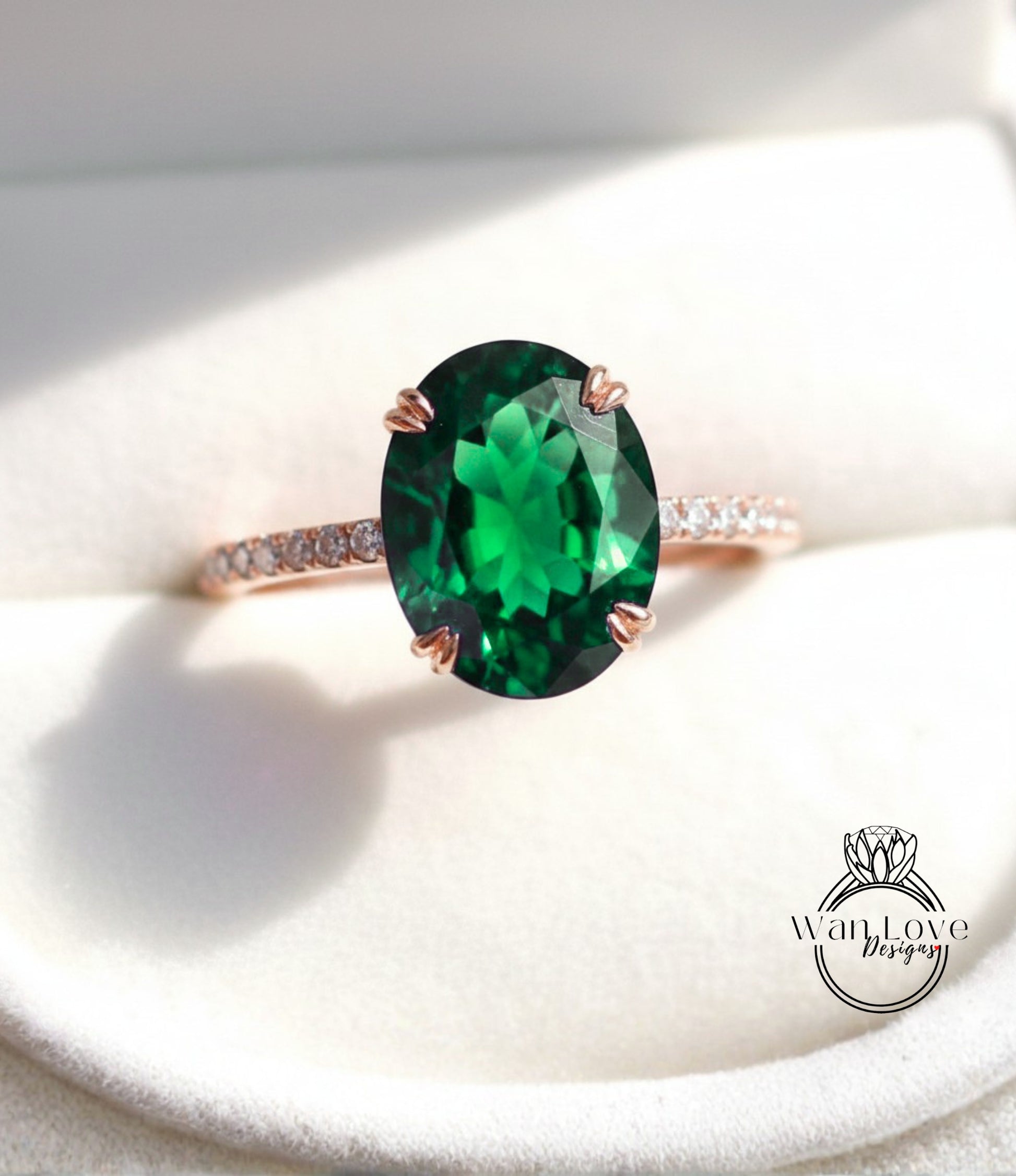 A close-up image of a rose gold ring with a large oval-shaped green gemstone, such as a diamond, set in the center of the band.