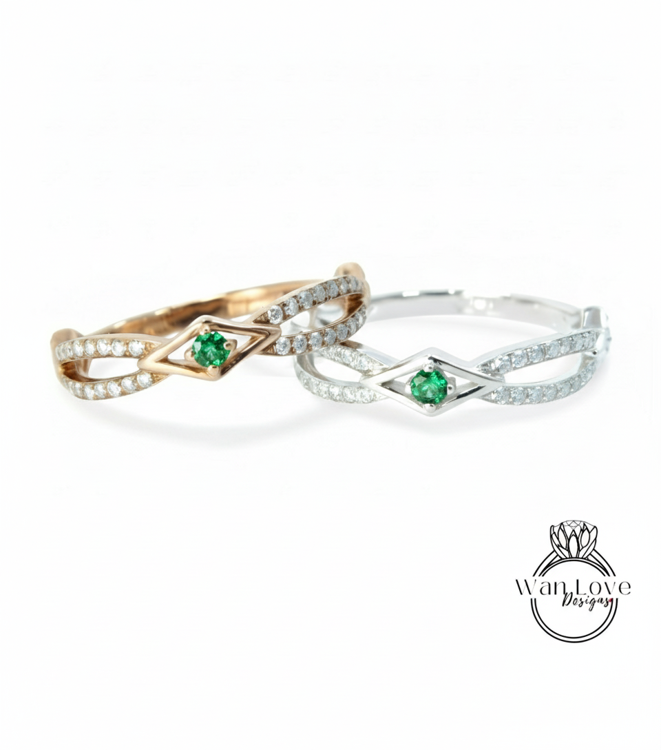 two rings with a diamond-encrusted design and a green gemstone, possibly a diamond or emerald, set in the center.