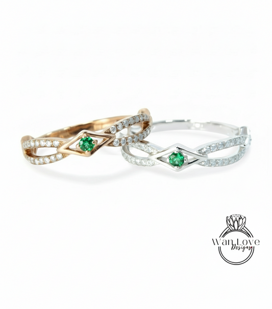 two rings with a diamond-encrusted design and a green gemstone, possibly a diamond or emerald, set in the center.