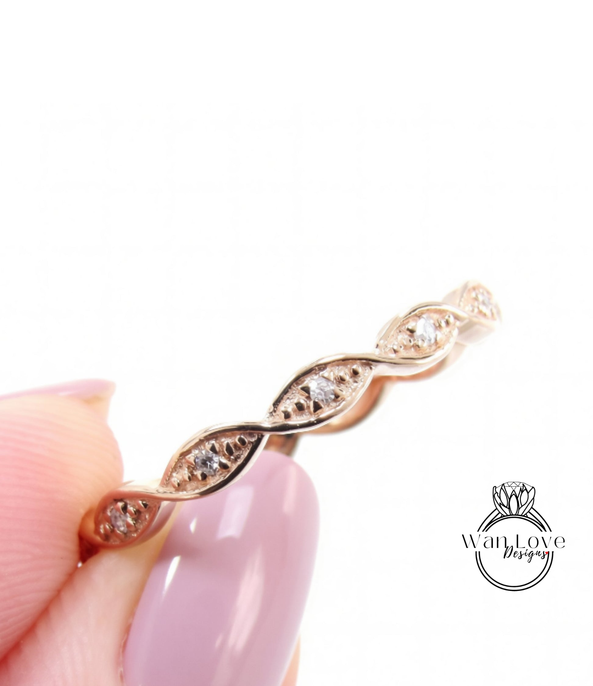 A close-up image of a person's hand holding a delicate gold ring with a row of small diamonds on the band.