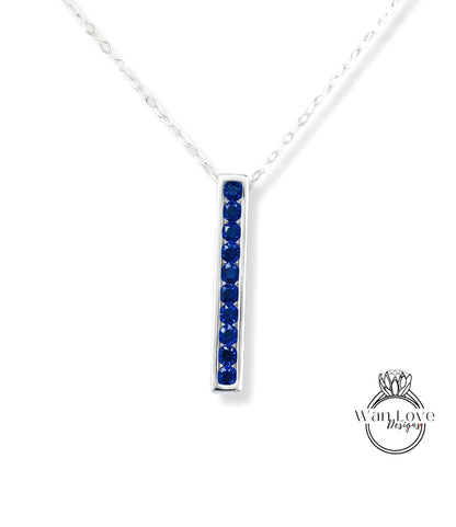 A silver necklace with a vertical row of blue gemstones, likely sapphires, set in a rectangular pendant.