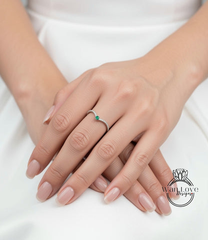 A close-up image of a person's hands wearing a ring with a green gemstone.