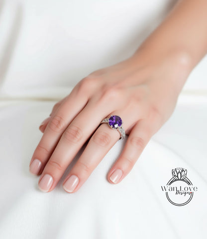 A close-up of a hand wearing a ring with a large purple gemstone.