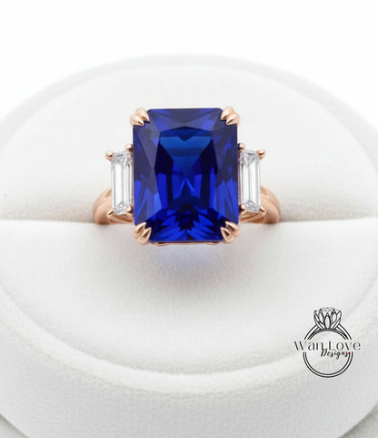 A large, blue gemstone ring with a gold band and three smaller diamonds on either side.