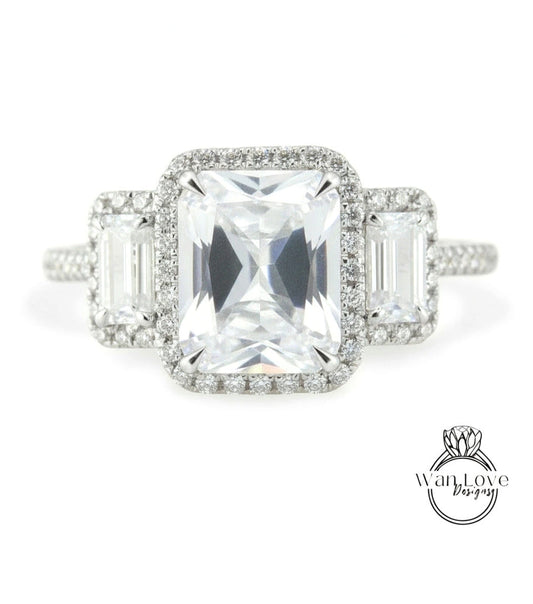 A close-up view of a diamond engagement ring with a large central diamond surrounded by smaller diamonds on either side.