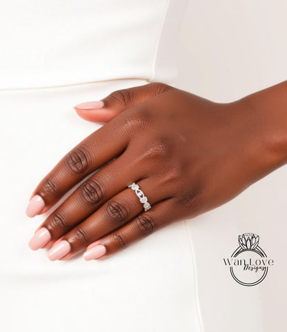 A close-up of a hand wearing a ring on the ring finger, with a white dress visible in the background.