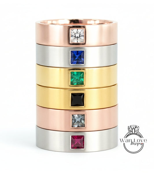 A stack of rings with various colored gemstones set in the center, including a ring with a large diamond and smaller diamonds in different colors.