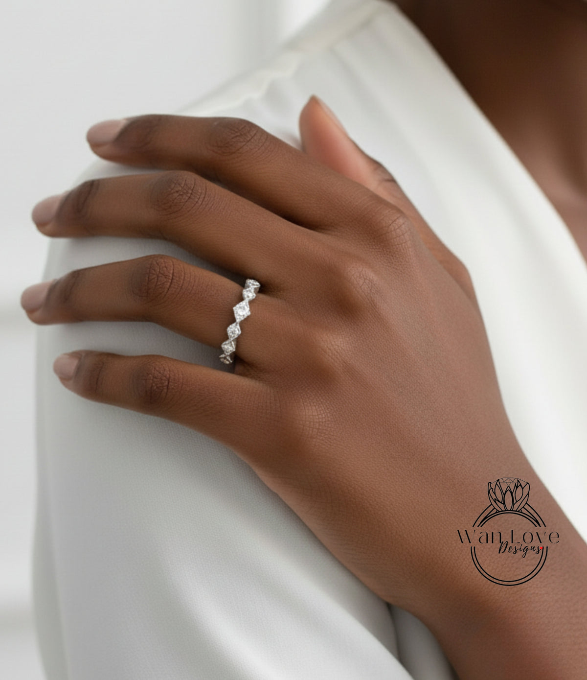 A close-up of a person's hand wearing a diamond ring on the ring finger.