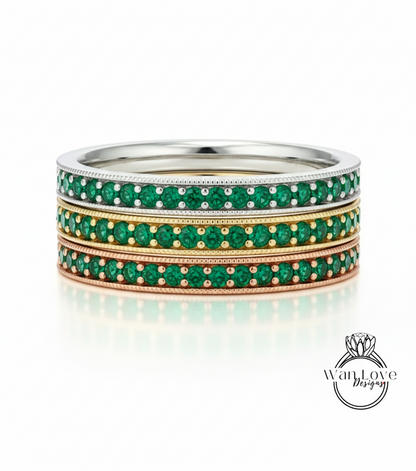 A stack of three rings with green gemstones set in a metallic band.